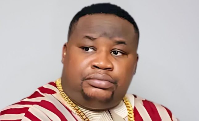 Cubana Chief Priest in a serious pose wearing a patterned shirt and gold chains, symbolizing his statement on naira spraying and EFCC crackdown.