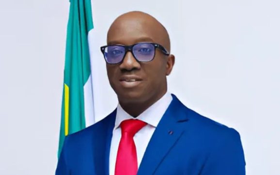 Governor Monday Okpebholo delivering a May Day speech outdoors at a stadium, standing behind a microphone in traditional attire.